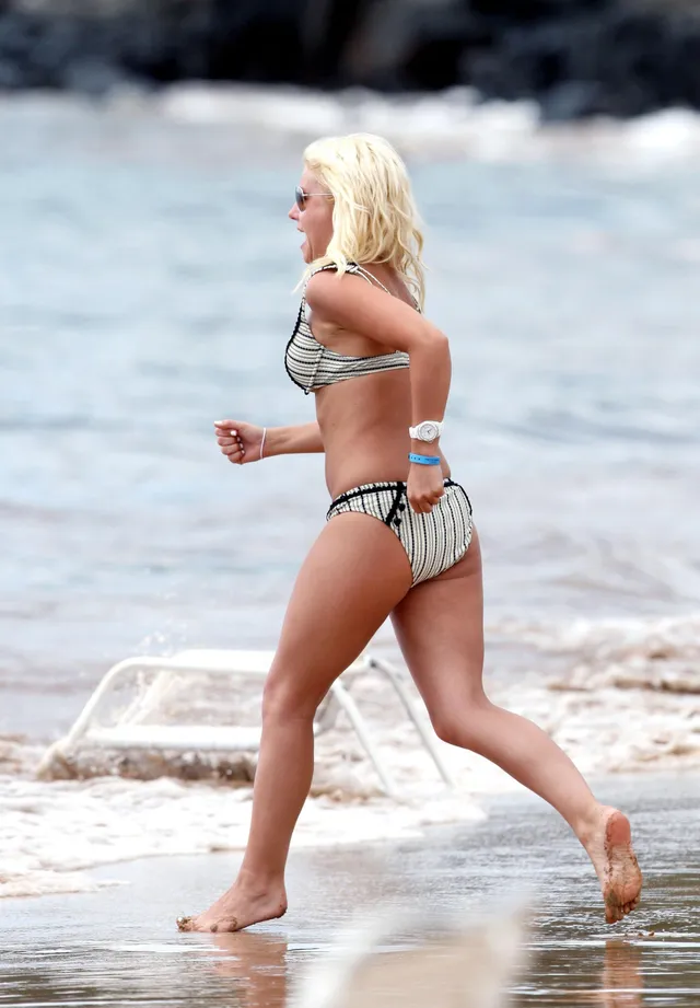 Elisha Cuthbert walking barefoot along the shoreline.