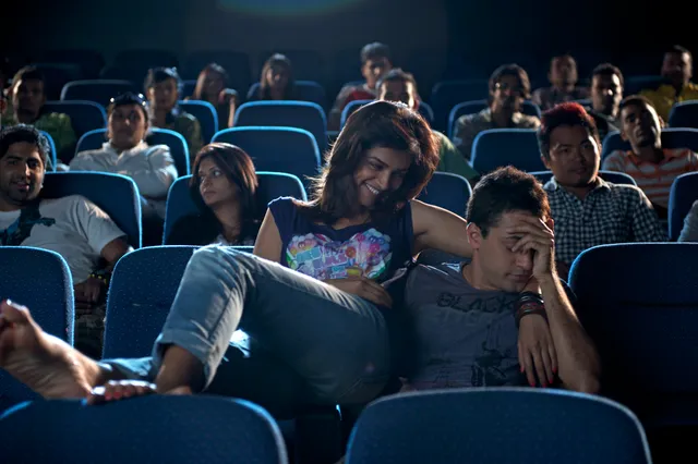 Deepika Padukone reclining barefoot in cinema seating during a screen scene.