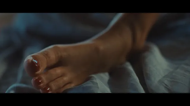 Adèle Exarchopoulos resting a bare foot in a dimly lit scene.