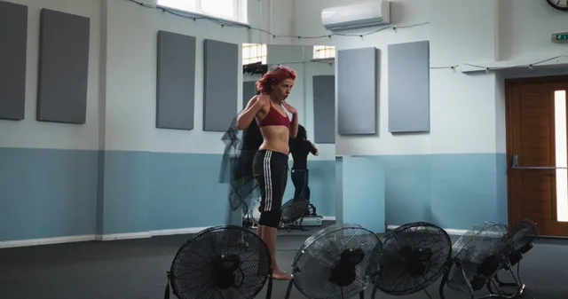 Naomi Scott standing barefoot beside floor fans.