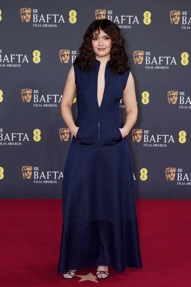 Olivia Cooke posing in a long dark blue outfit.