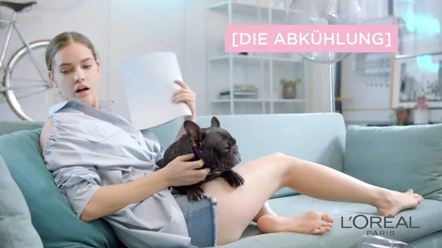 Barbara Palvin reclining barefoot on a sofa with papers.