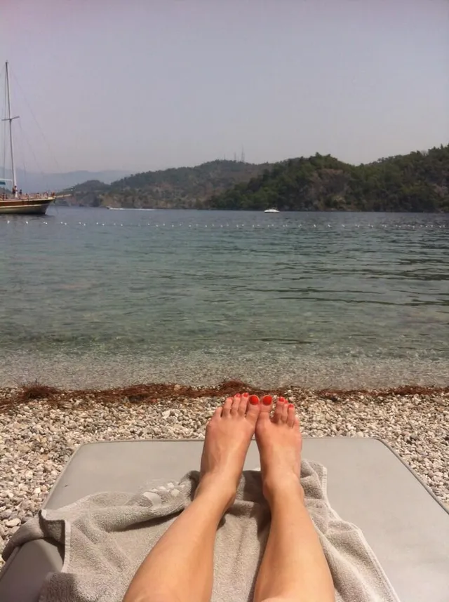 Phoebe Dynevor relaxing beside a lakeside beach.