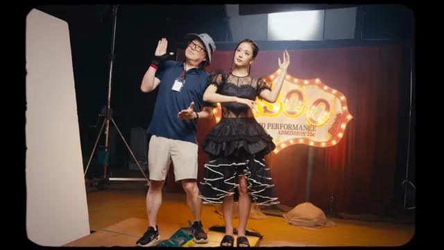 Jisoo sitting beside a companion in dark heels during a studio appearance.