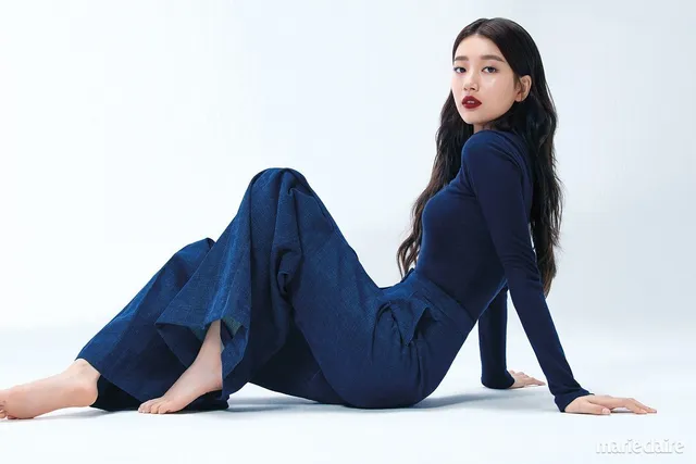 Bae Suzy sitting barefoot in a dark denim outfit.