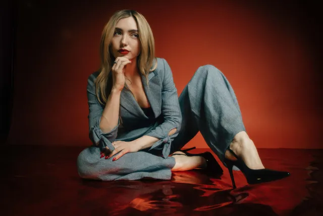Peyton List sitting barefoot in a pale blue suit.