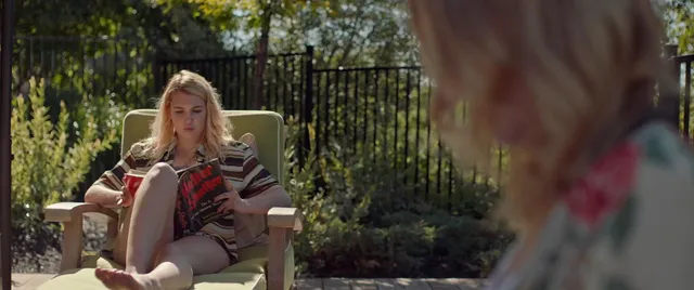 Sophie Nélisse sitting barefoot in an outdoor chair in a film scene.
