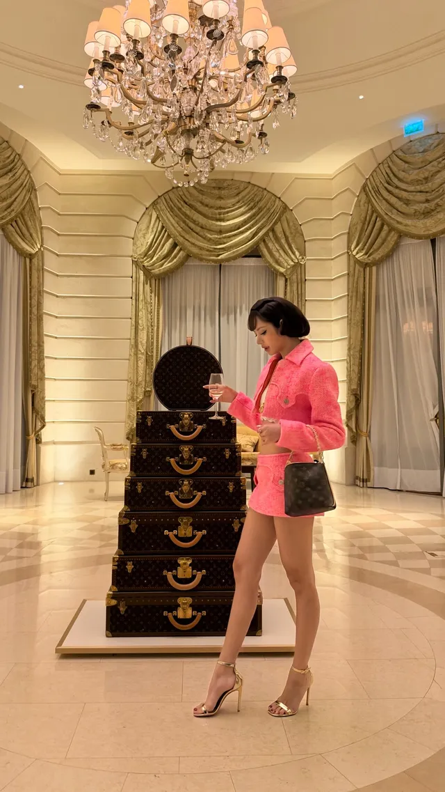 Lisa (Lalisa Manobal) wearing gold heels and dark shorts with a pink jacket at a jewellery display.