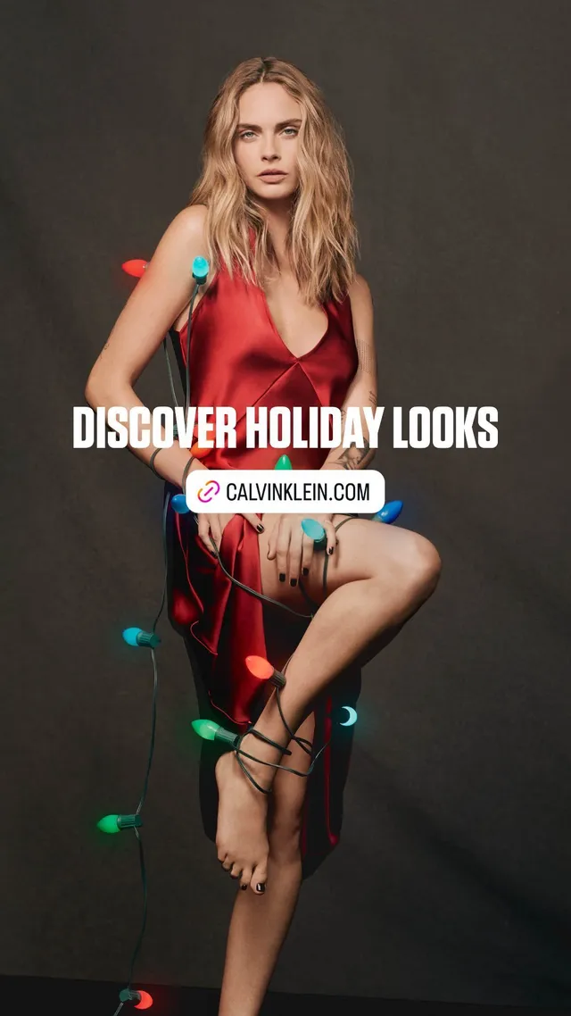 Cara Delevingne posing in a red dress with decorative holiday lights.