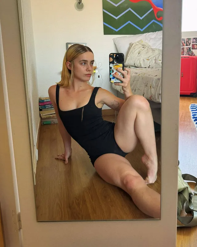 Clara Galle taking a mirror selfie barefoot in a black outfit.