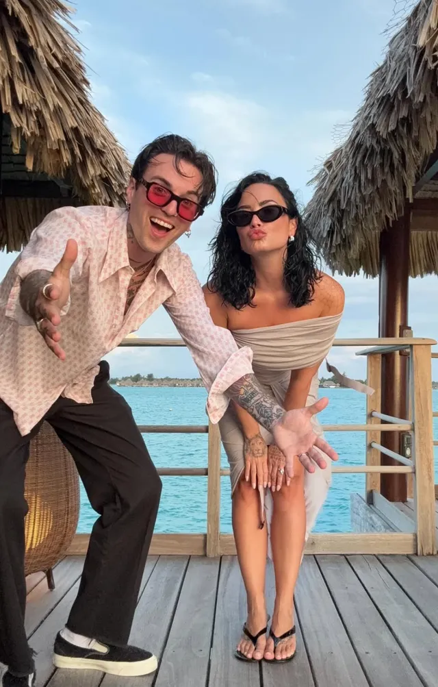Demi Lovato standing beside another person on a deck in flip-flops.