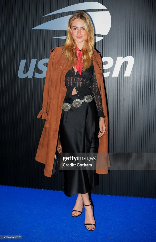 Grace Van Patten posing in a brown coat and black heels at the US Open.
