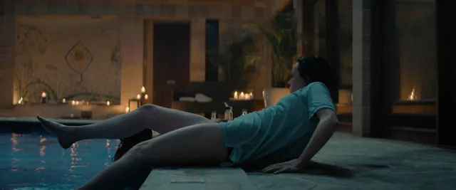 Daisy Ridley sitting beside an indoor pool in a screen scene.