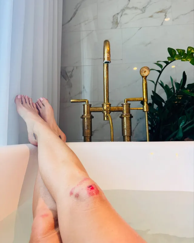 Katy Perry resting bare feet over a bathtub.