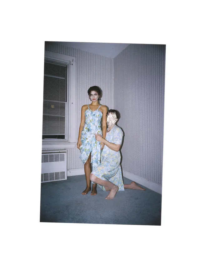 Zendaya posing barefoot beside another person for an indoor portrait.