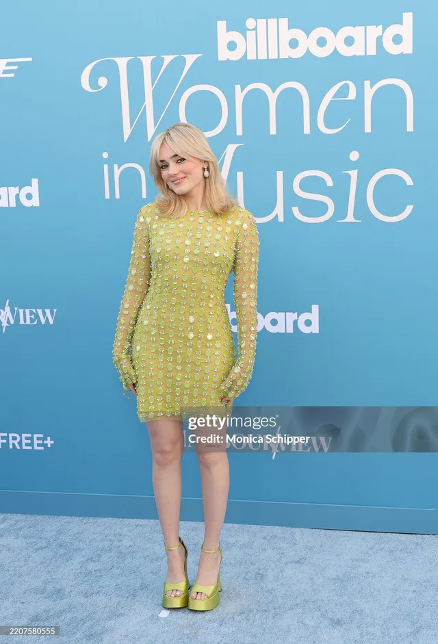 Meg Donnelly wearing a bright green mini dress and platform heels at a music event.