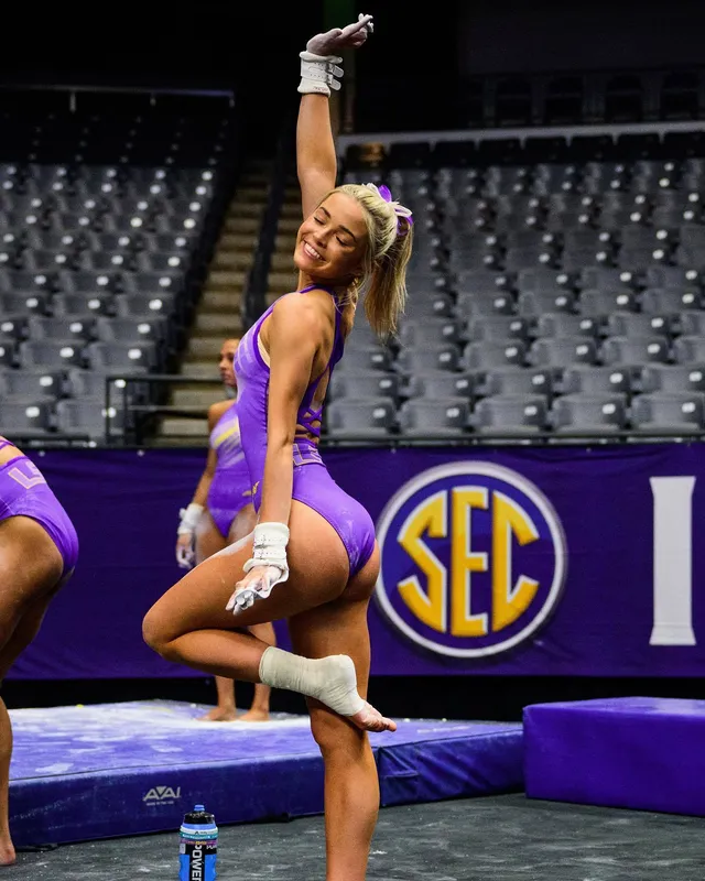 Olivia Dunne posing beside competition equipment in a purple leotard.