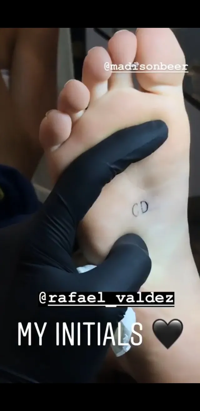 Madison Beer showing a foot tattoo in a close-up.