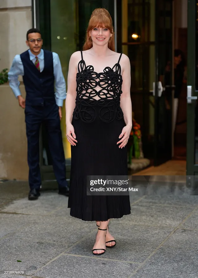 Bryce Dallas Howard walking outdoors in a long black dress.