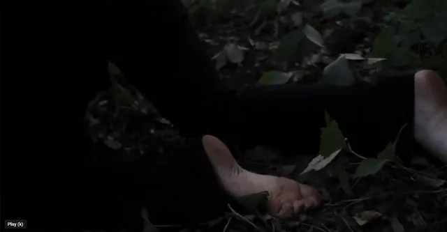 Victoria Pedretti lying on the ground during a dark screen scene.