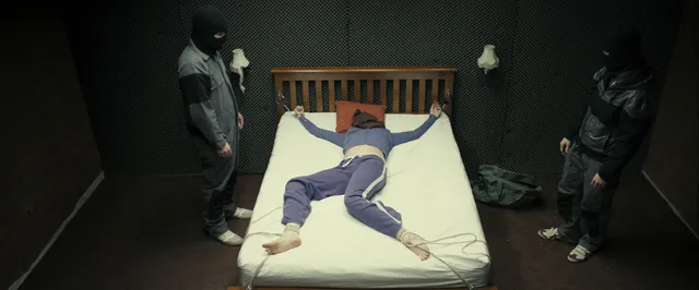 Gemma Arterton lying on a bed with other performers nearby.