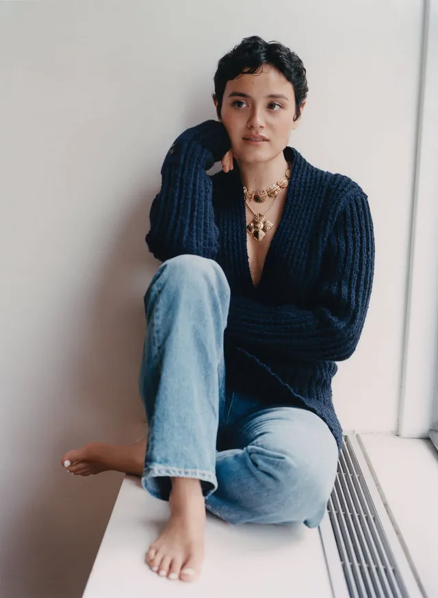 Chase Sui Wonders sitting barefoot in jeans beside a window.