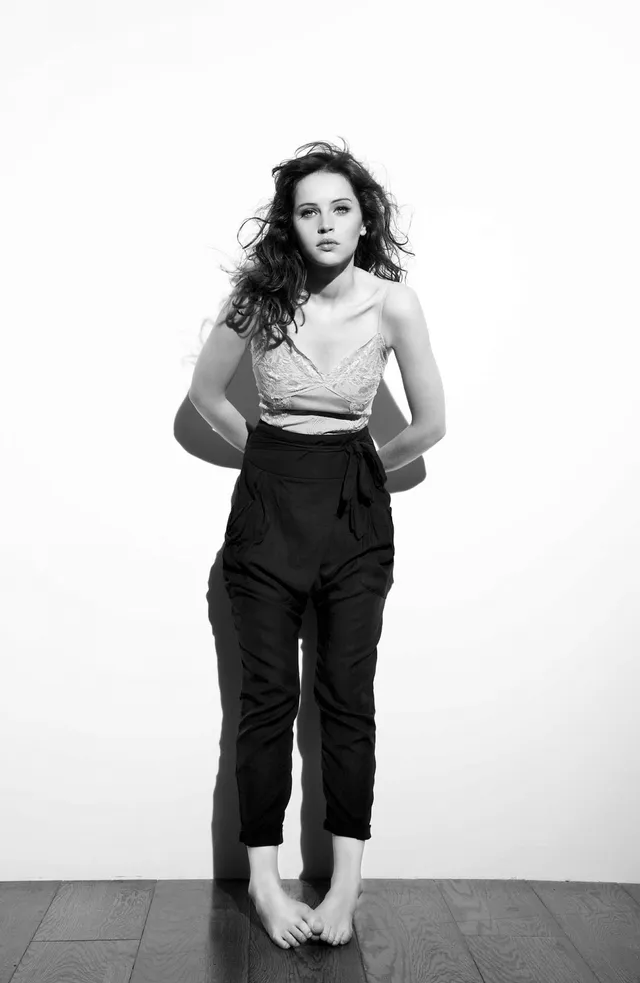 Felicity Jones standing in a monochrome studio portrait.
