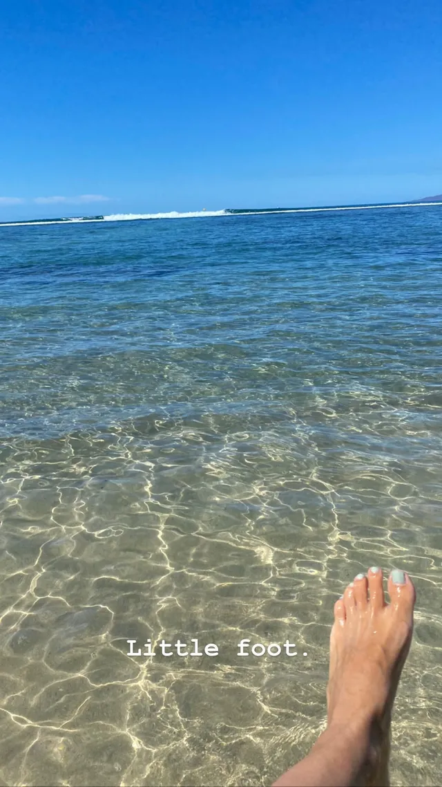 Rachel Bilson resting a bare foot beside clear sea water.