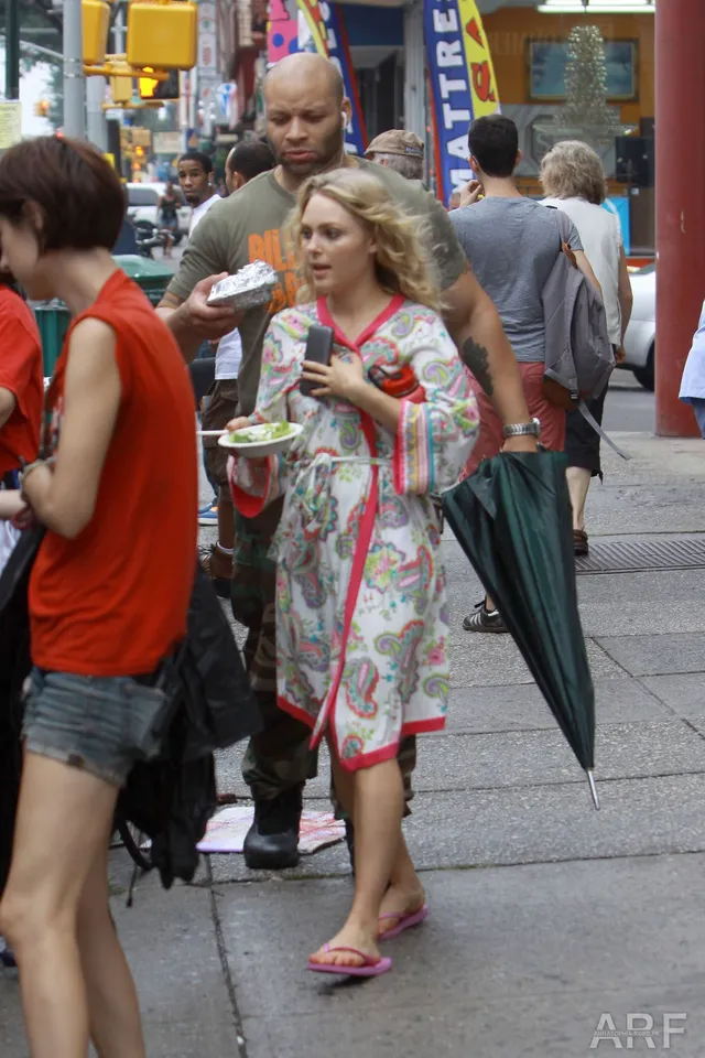 AnnaSophia Robb walking in a patterned robe and pink flip-flops.