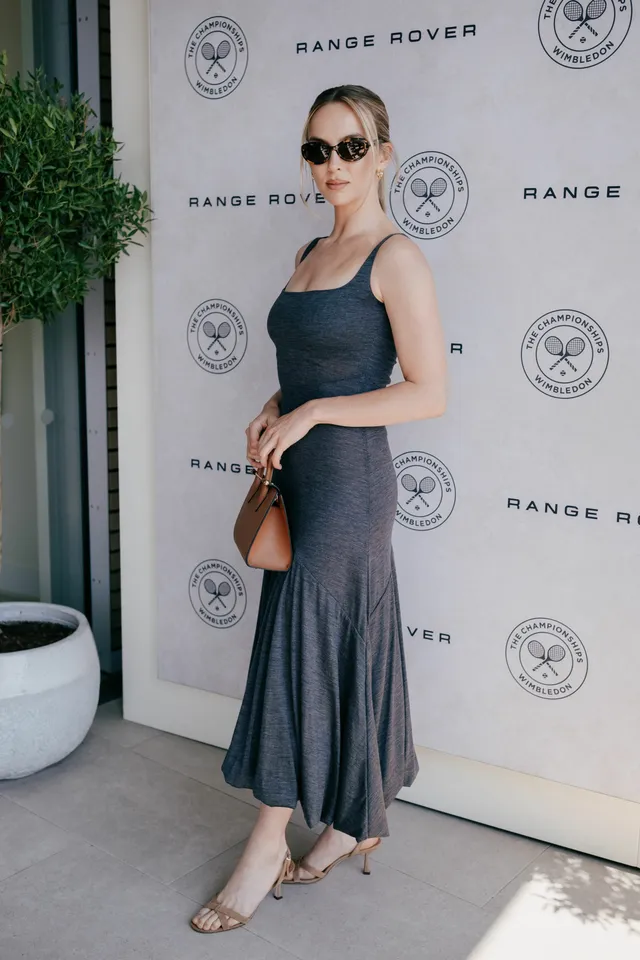 Jodie Comer posing against an event backdrop in a grey dress.