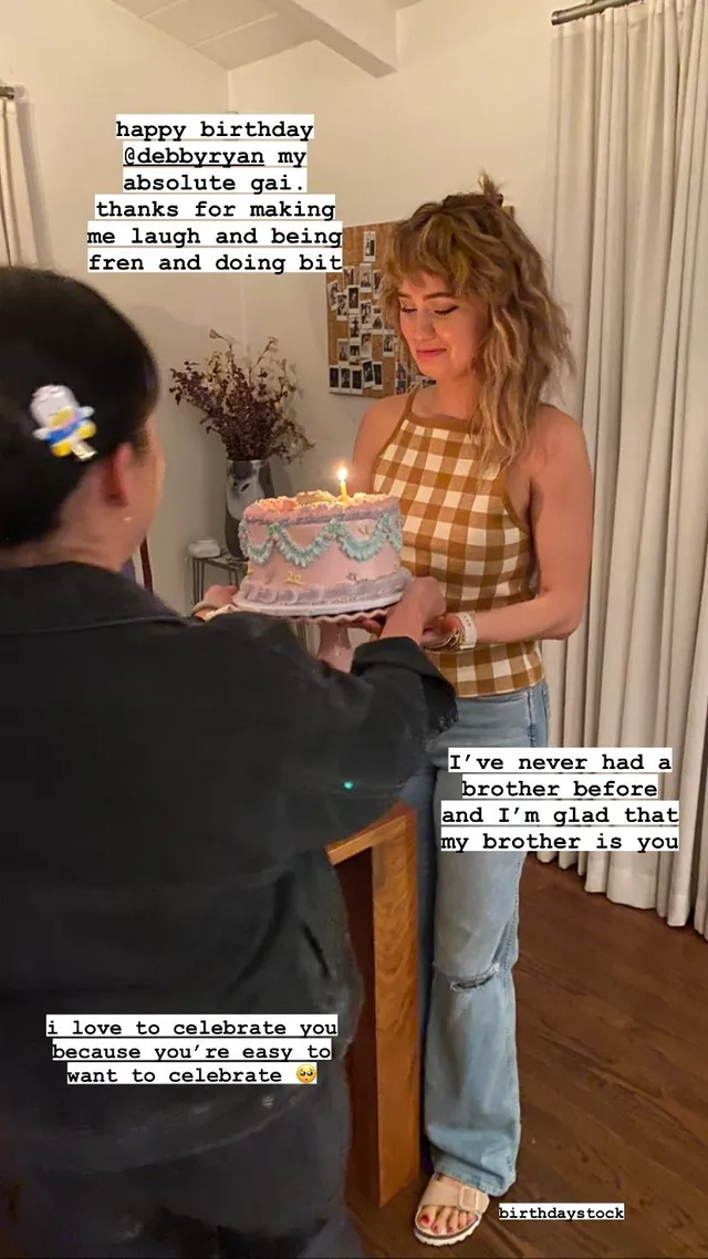 Debby Ryan celebrating indoors in a checked top.