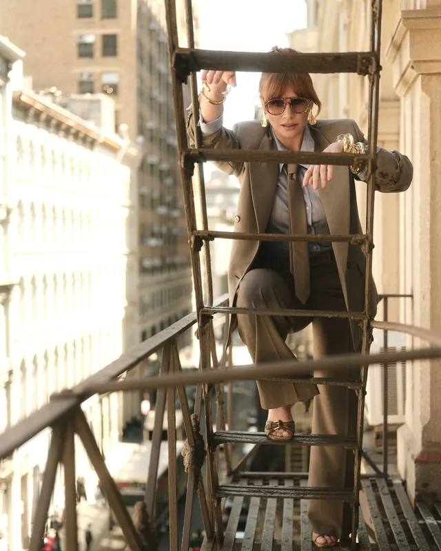 Bryce Dallas Howard posing on a fire escape in a grey outfit.