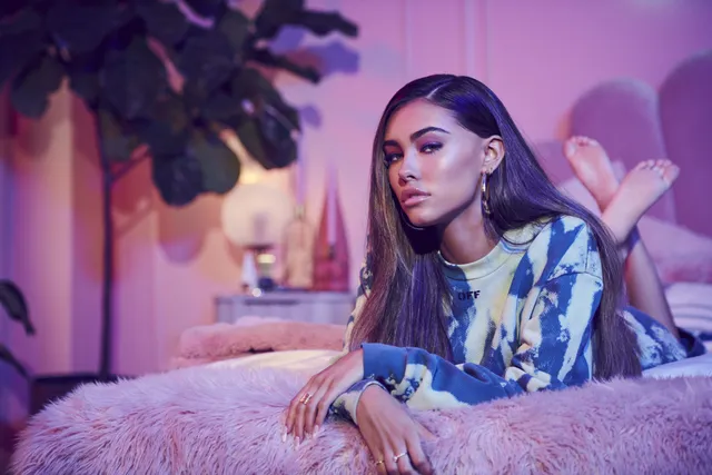 Madison Beer: reclining barefoot on a pink sofa with feet raised.