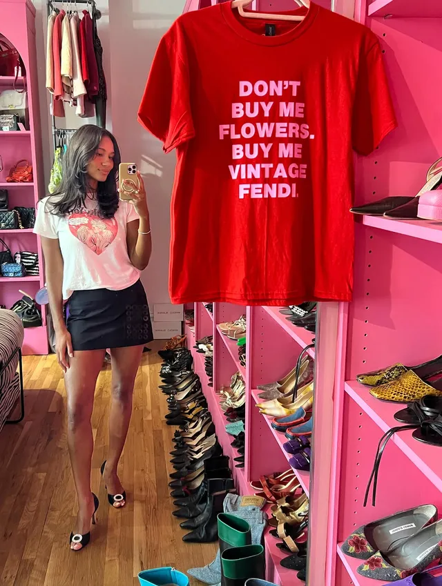 Greta Onieogou taking a mirror selfie in a white top, dark skirt and patterned heels.