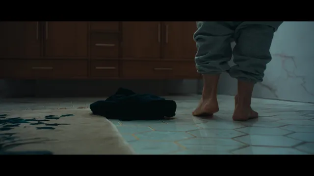 Jessica Biel standing barefoot on a tiled floor in a screen scene.