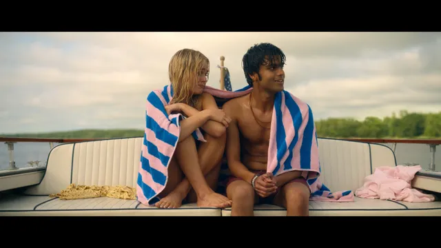 Emily Alyn Lind sitting barefoot with a man in a boat scene.
