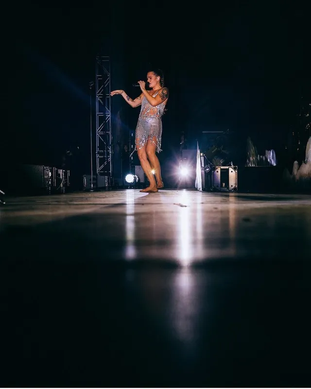 Tove Lo performing barefoot on stage in a sparkling outfit.