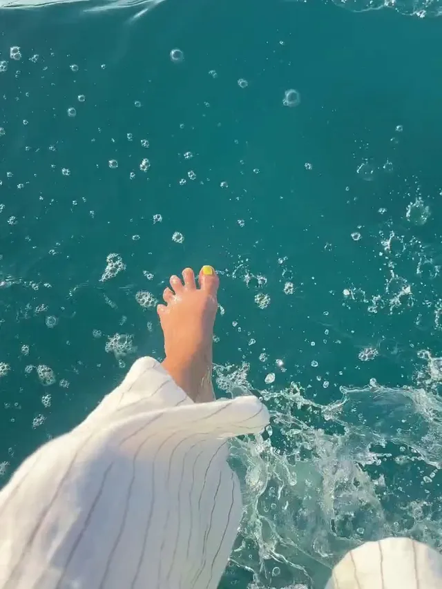 Victoria Justice extending a bare foot over turquoise water.