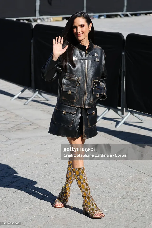Jennifer Connelly walking outside a venue in a denim outfit and patterned boots.