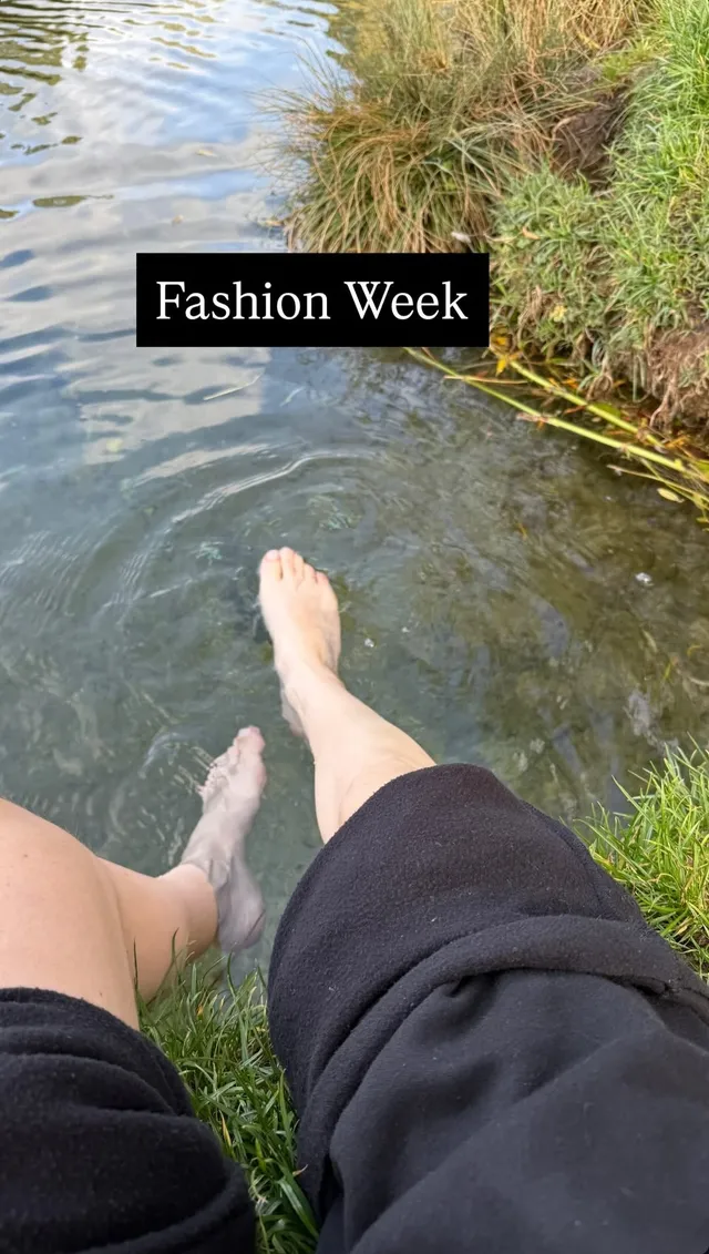 Ellie Goulding extending a bare foot over water.