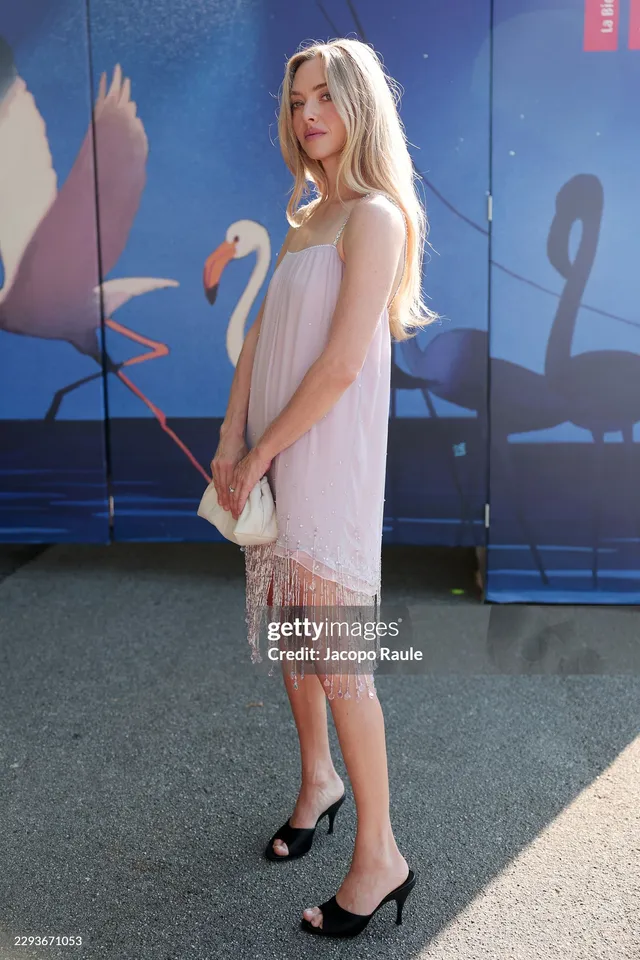Amanda Seyfried standing outdoors in a fringed dress and black heels.