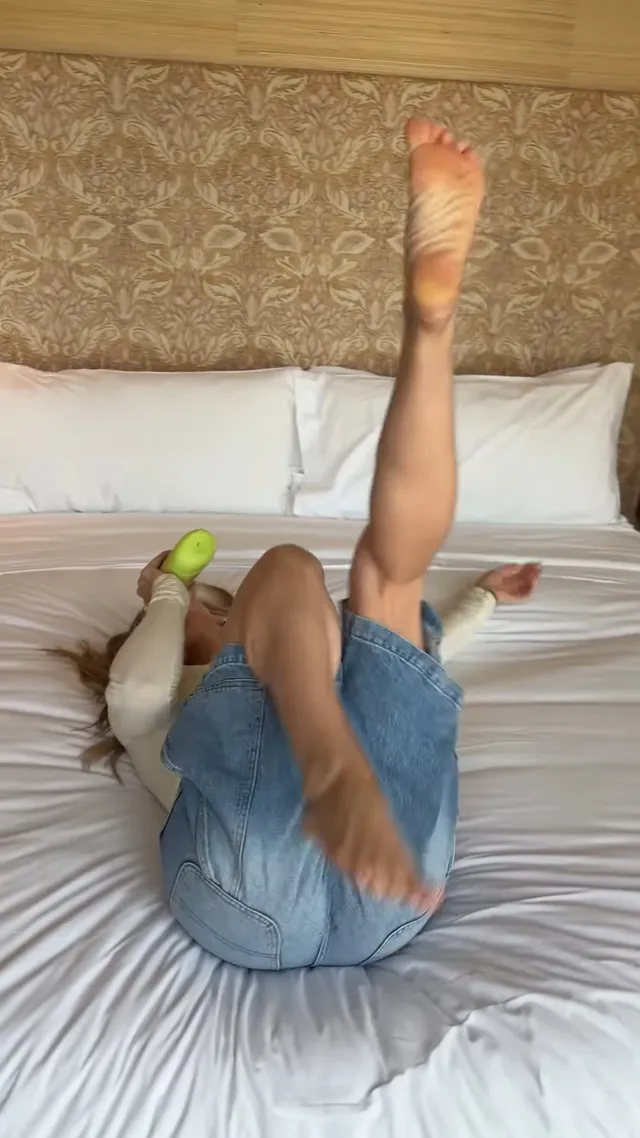 Hilary Duff lying on a bed with bare feet extended upward.