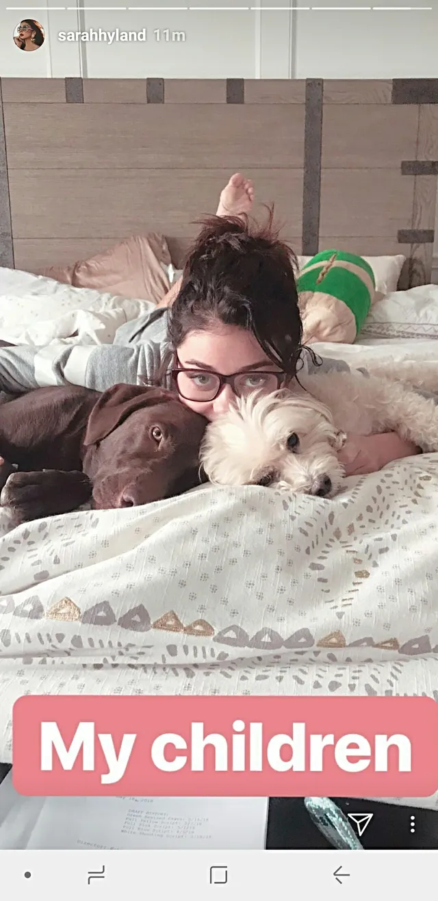 Sarah Hyland lying on a bed with dogs.