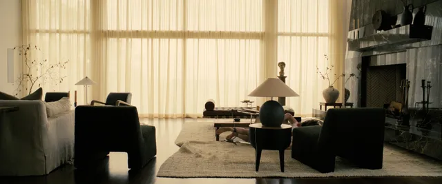 Sophie Thatcher sitting barefoot across from a man in a spacious room.