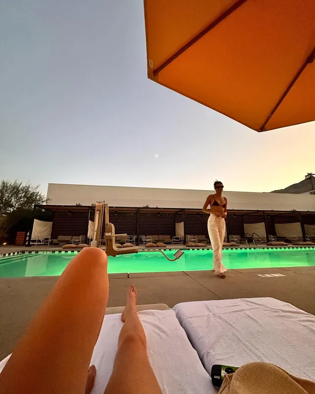Adelaide Kane resting her feet beside a swimming pool.