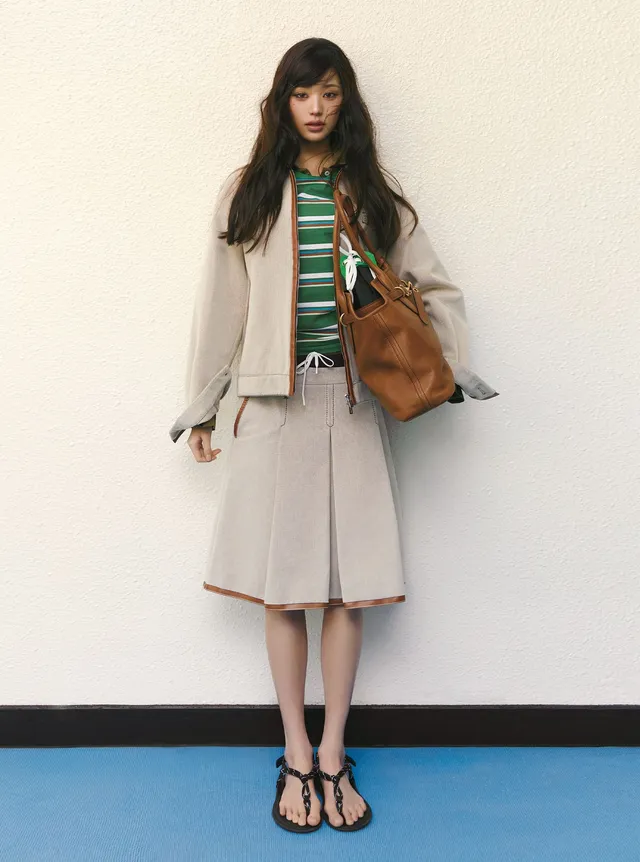 Jang Wonyoung standing in a pale outfit and flat sandals.