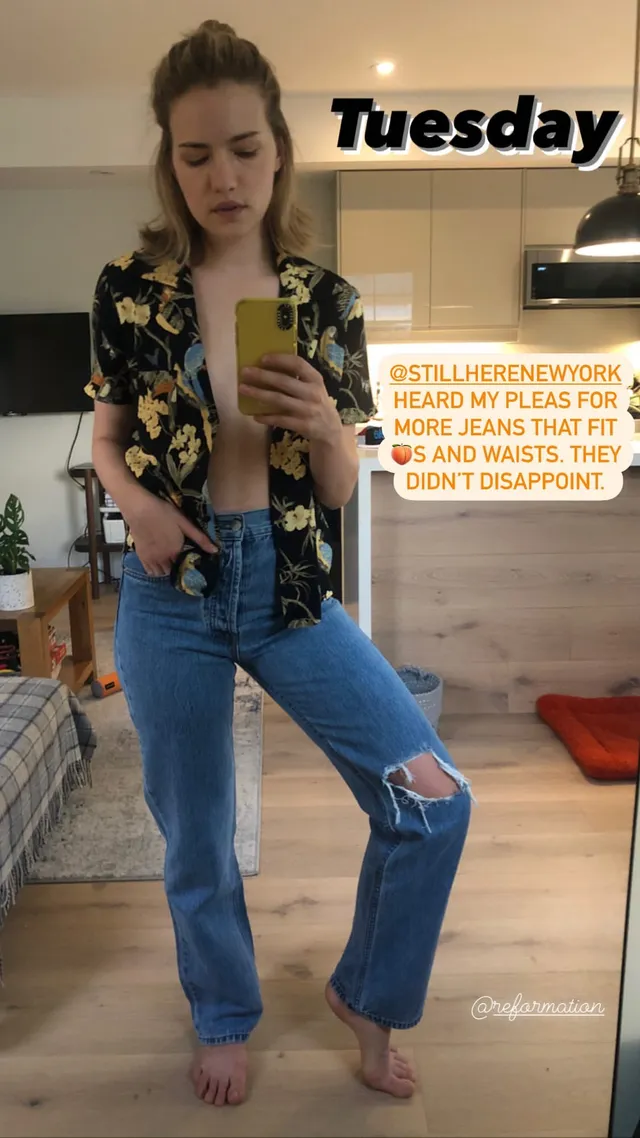 Willa Fitzgerald taking a mirror photograph barefoot in jeans.