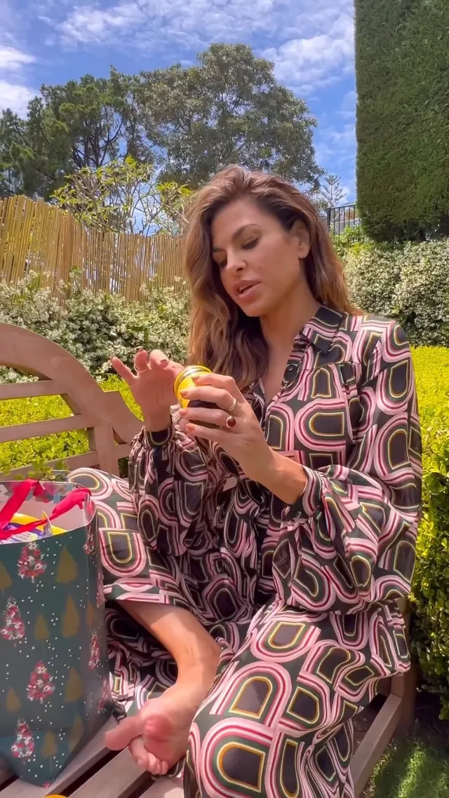 Eva Mendes sitting outdoors in a patterned dress.