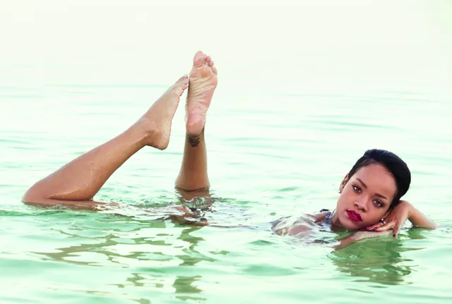 Rihanna floating in water with her bare feet raised behind her.