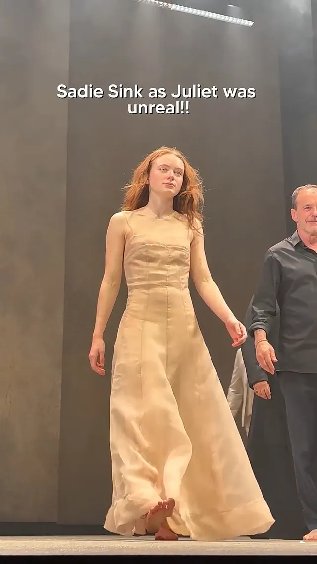 Sadie Sink walking barefoot onstage in a long pale dress.